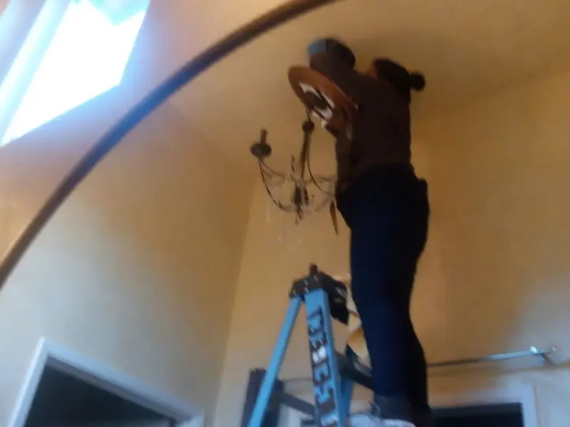 Electrician installing a chandelier in a Lubbock residence